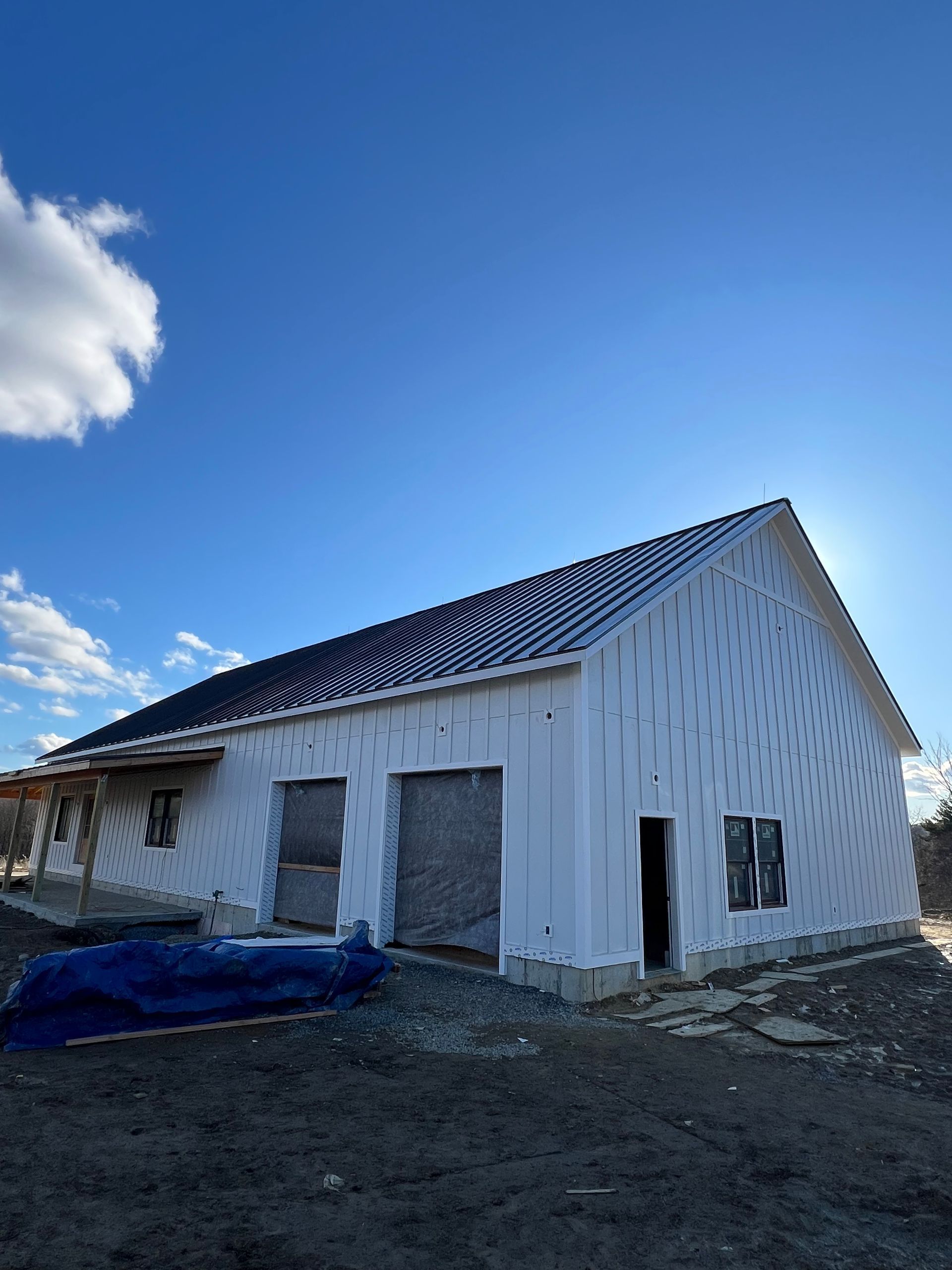 A newly constructed building under a bright blue sky, with white exterior insulation and a dark roof.