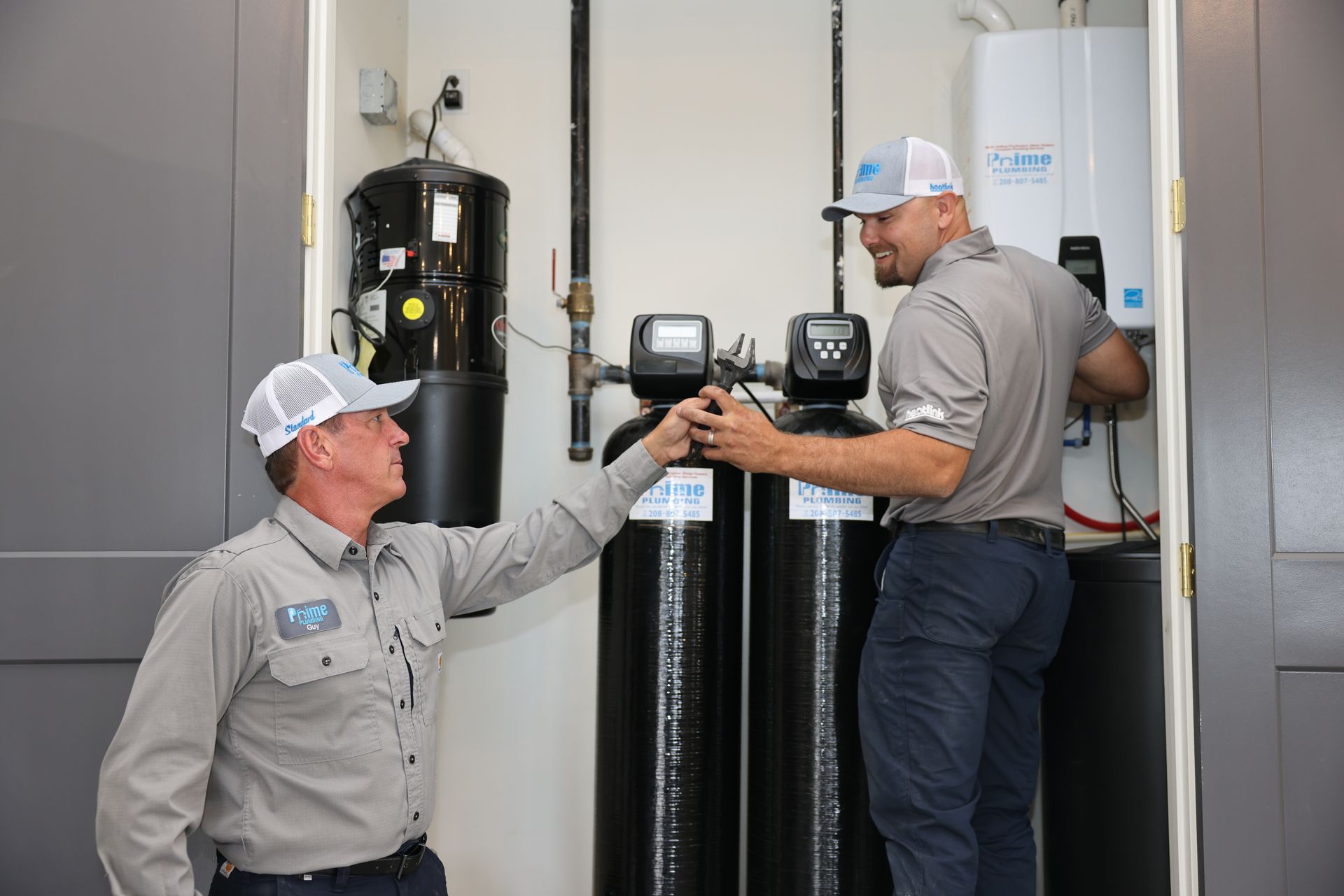 Two technicians fist-bumping in a utility room with water filtration equipment.