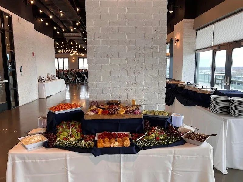 A buffet table with appetizers and charcuterie boards set up in a bright, modern room with brick walls.