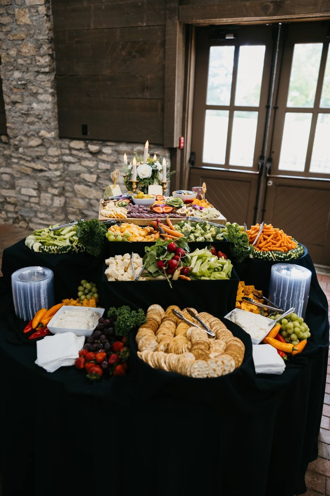 Buffet table with pastries, fruit, and appetizers in a rustic room with stone walls and a wooden door