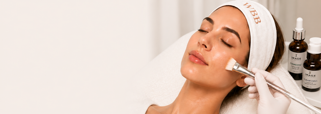Woman receiving a facial treatment with a mask brush in a spa setting