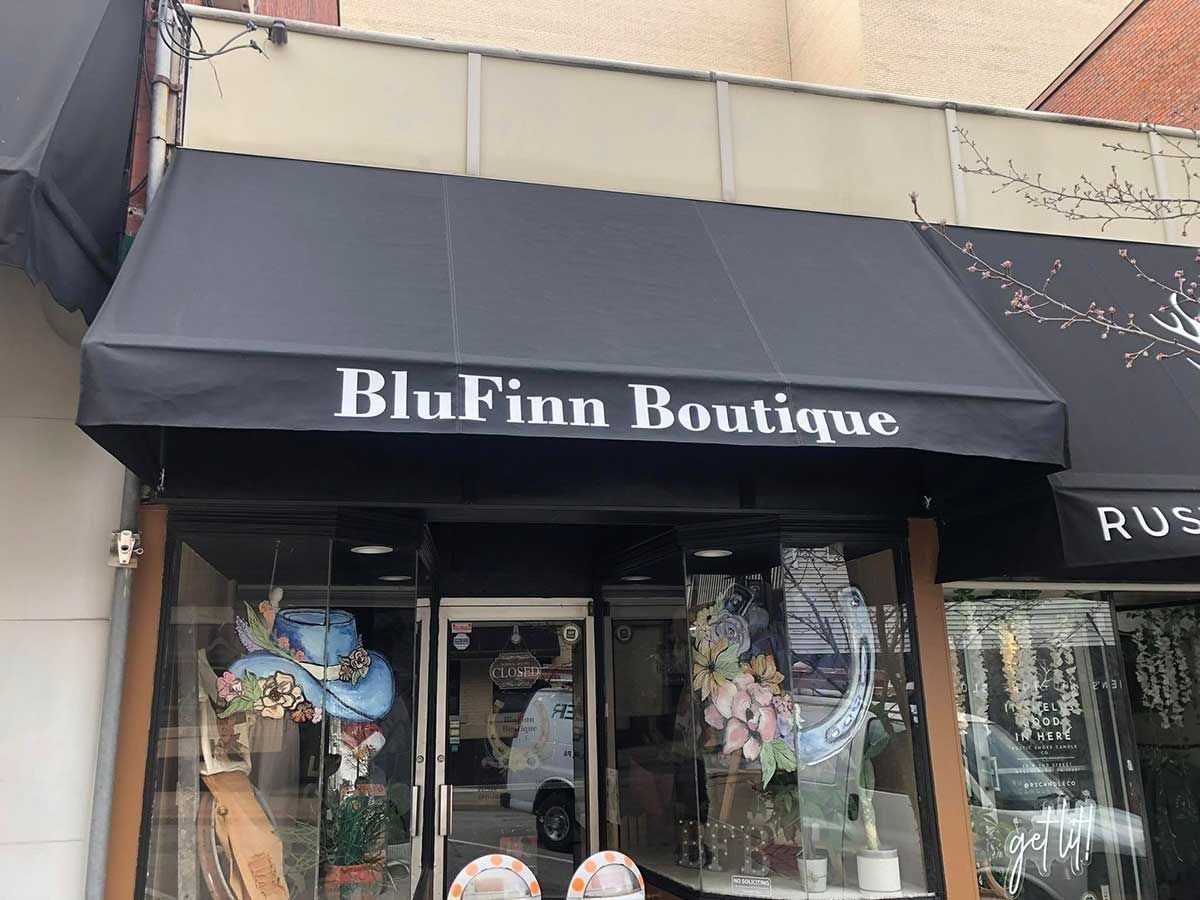 BluFinn Boutique storefront with a black awning and display window. The shop name is in white letters.