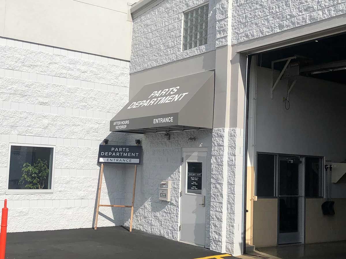 A white building with a gray awning that says auto department