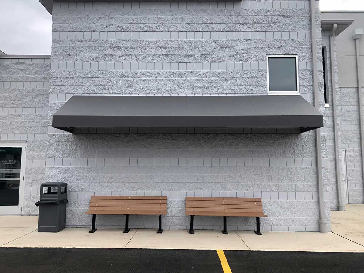 A brick building with a canopy over it and two benches in front of it.