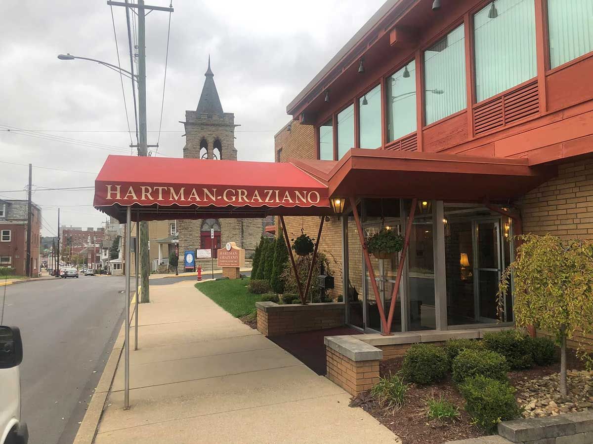 A building with a red awning that says ' hariman graziano ' on it