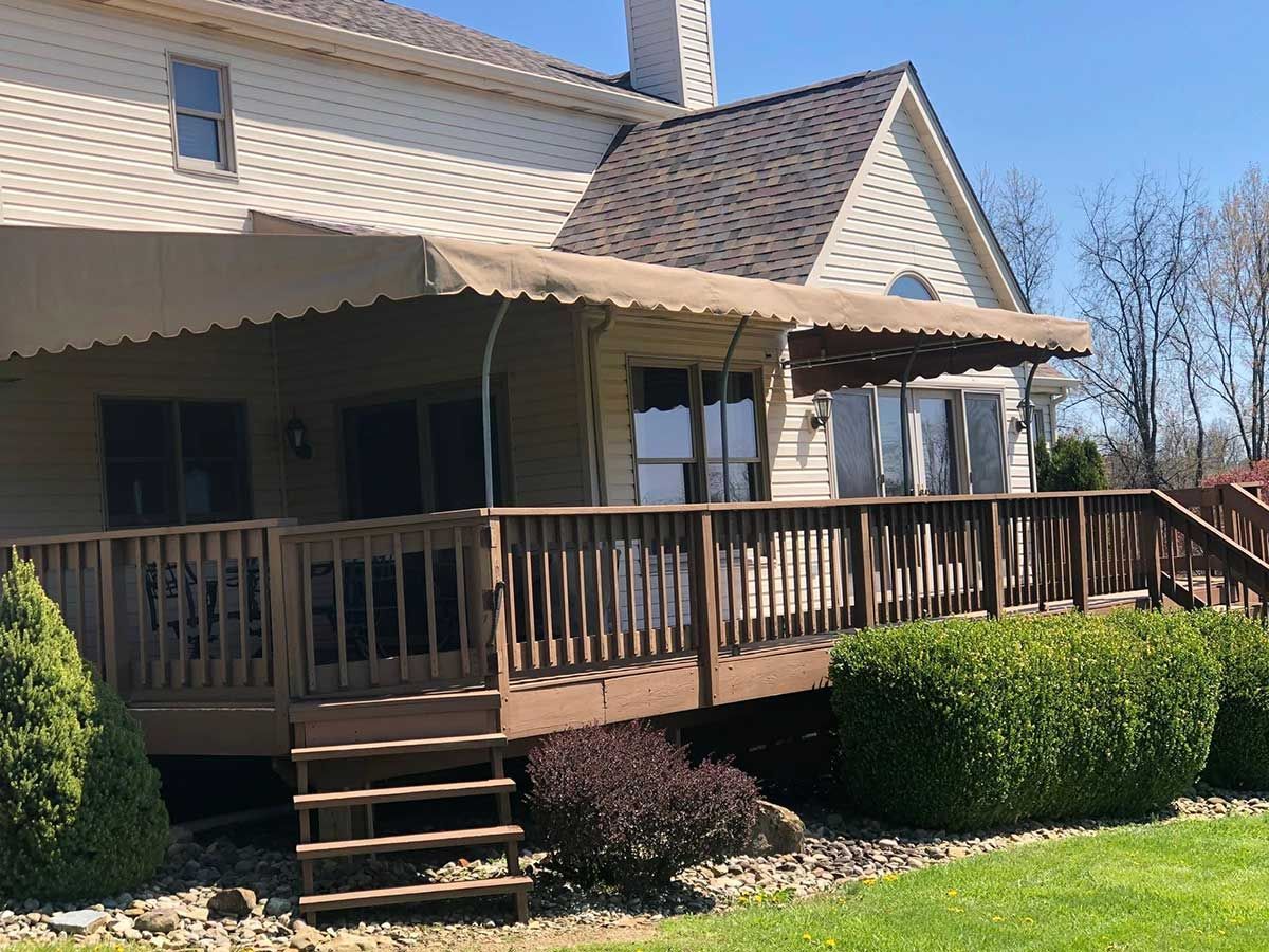 A large deck with a canopy over it is in front of a house.