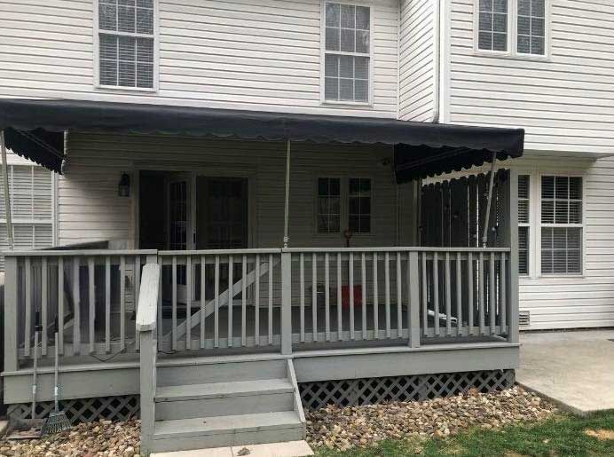 A white house with a black awning on the porch