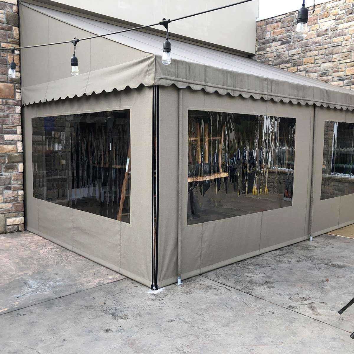 A tent with clear windows is sitting in front of a brick building.