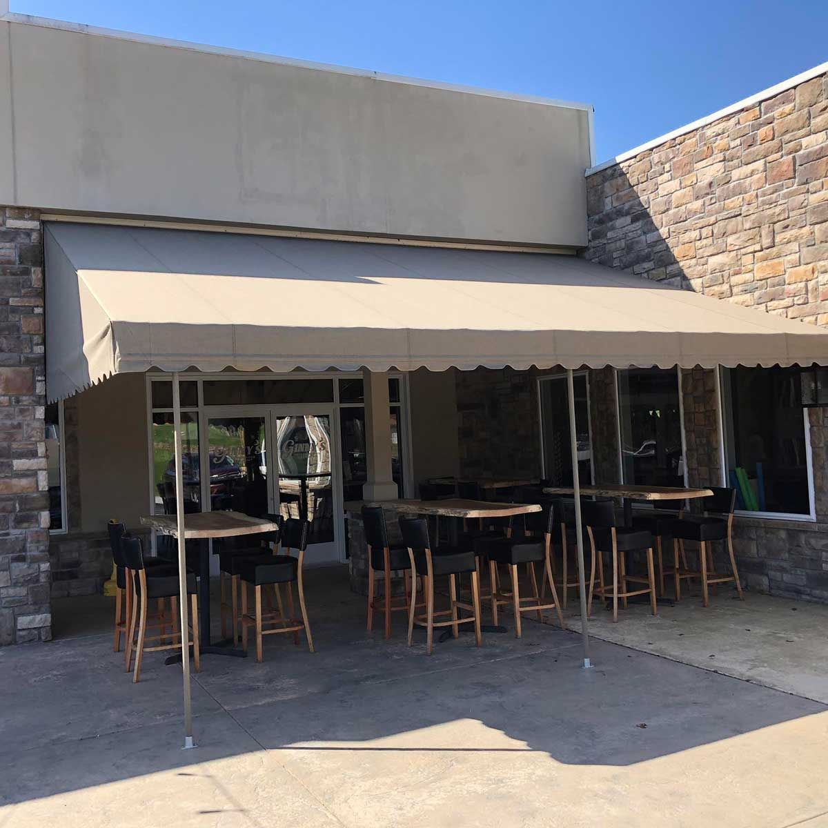 A restaurant with tables and chairs under an awning