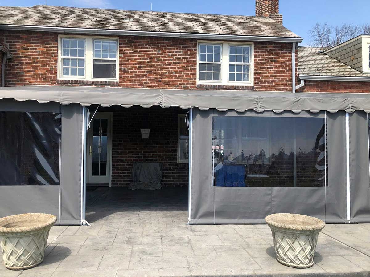 A large tent is sitting in front of a brick house.