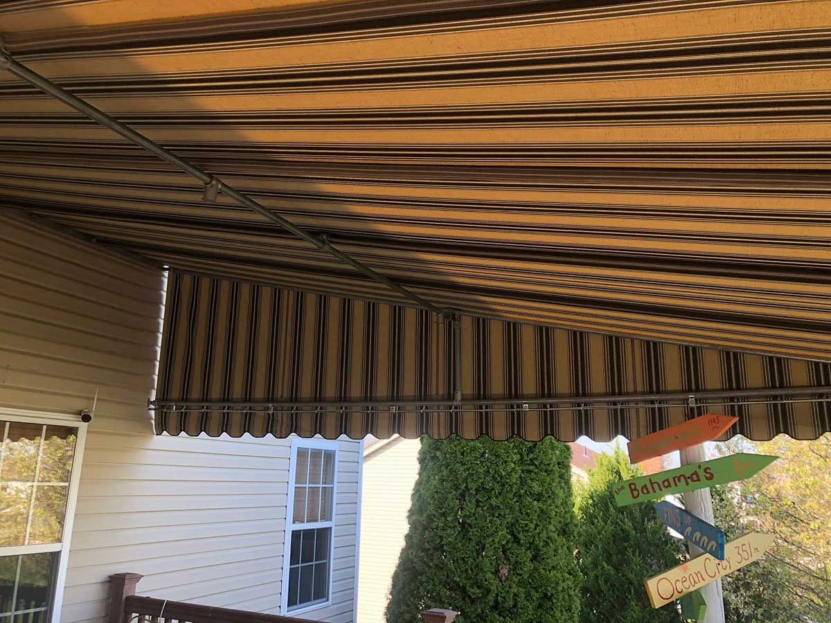 A porch with a striped awning over it.
