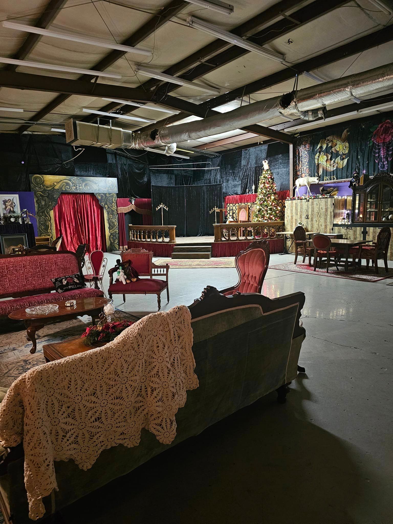 Display of ornate furniture and draped textiles in a large warehouse-like showroom