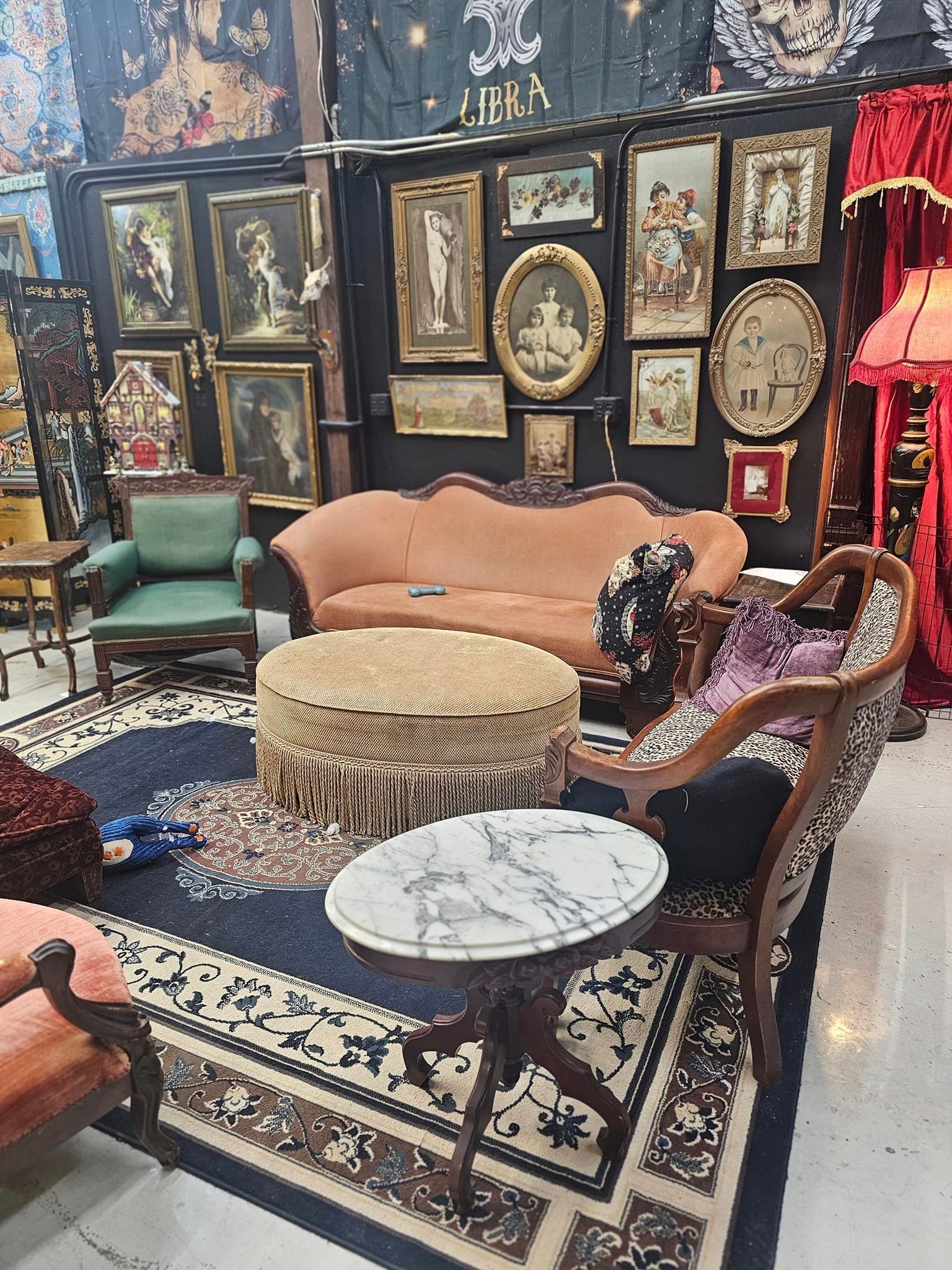 Elegant lounge with ornate wallpaper, peach sofa, round marble table, patterned rug, and vintage chairs