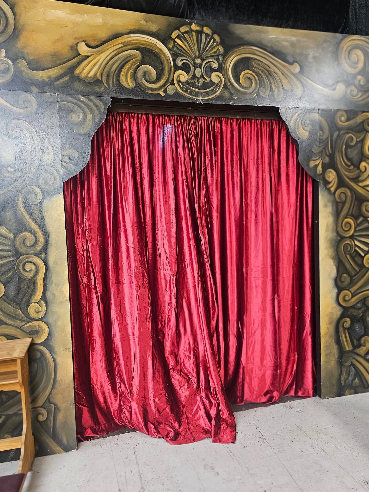 Red velvet curtains at a decorated black-and-gold stage entrance.