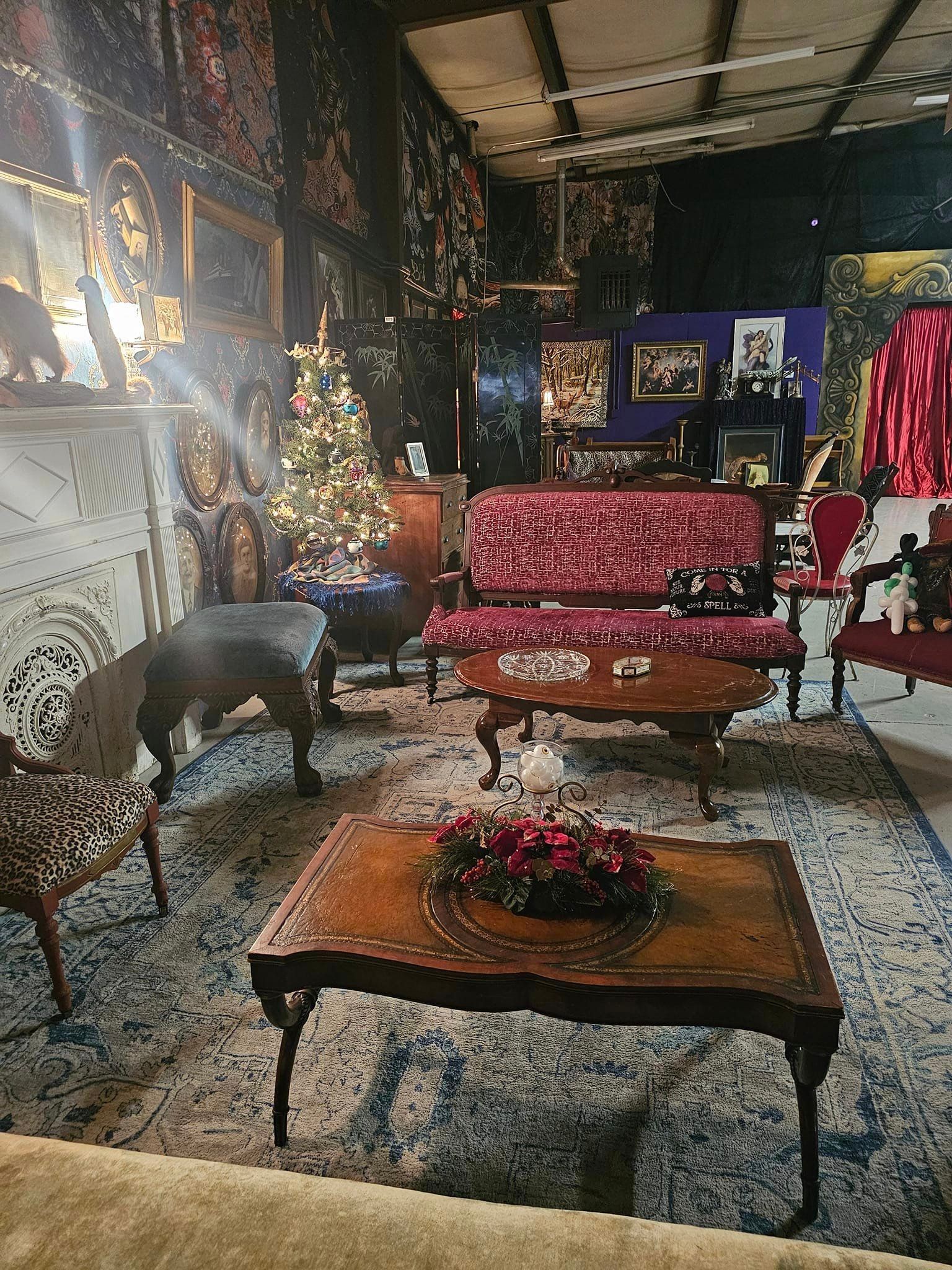 Decorated living room with red sofa, patterned chairs, floral table, and ornate wall art