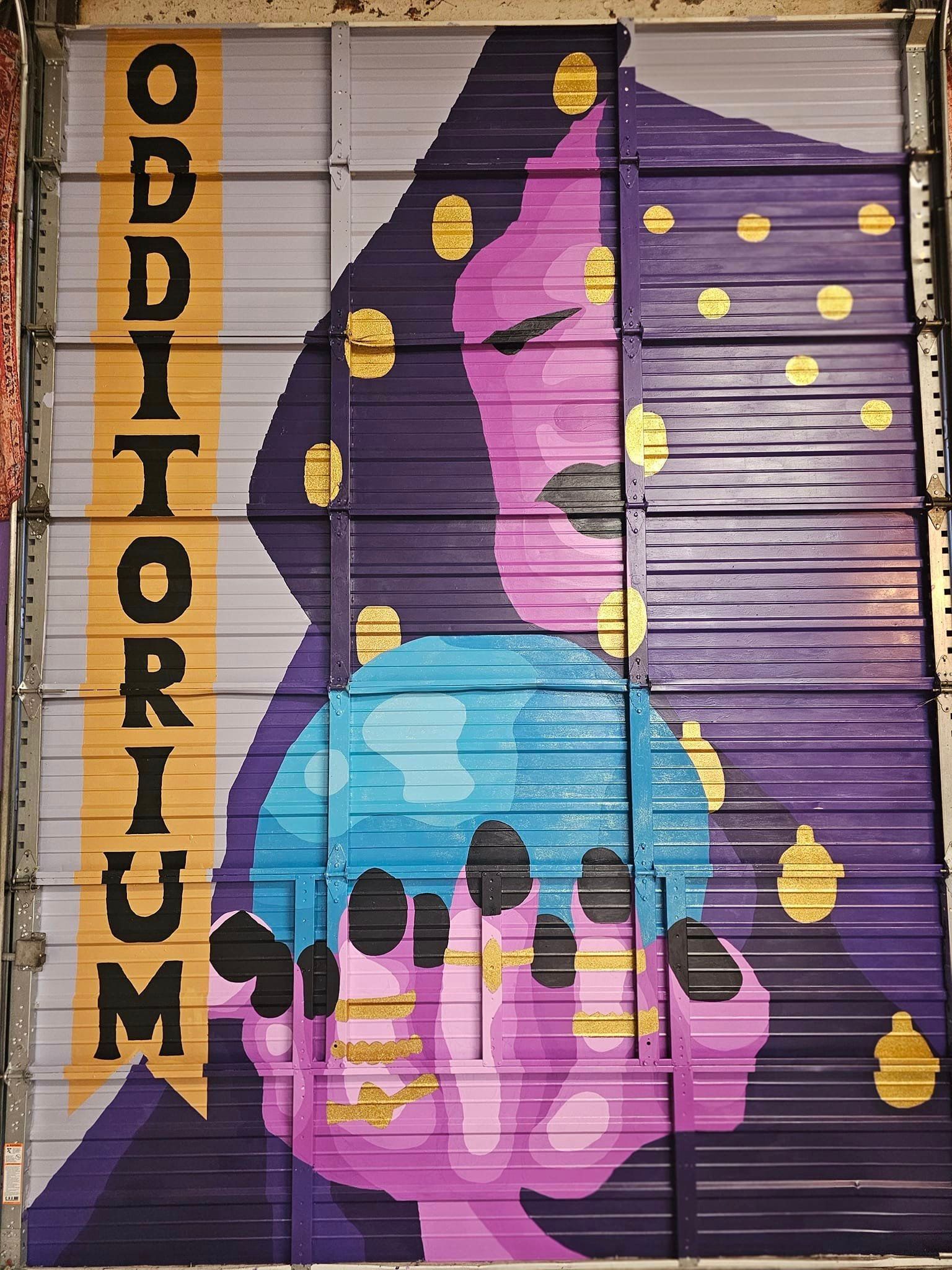 Colorful mural with a purple abstract face, blue skull, yellow dots, and vertical “ODDITORIUM” text.