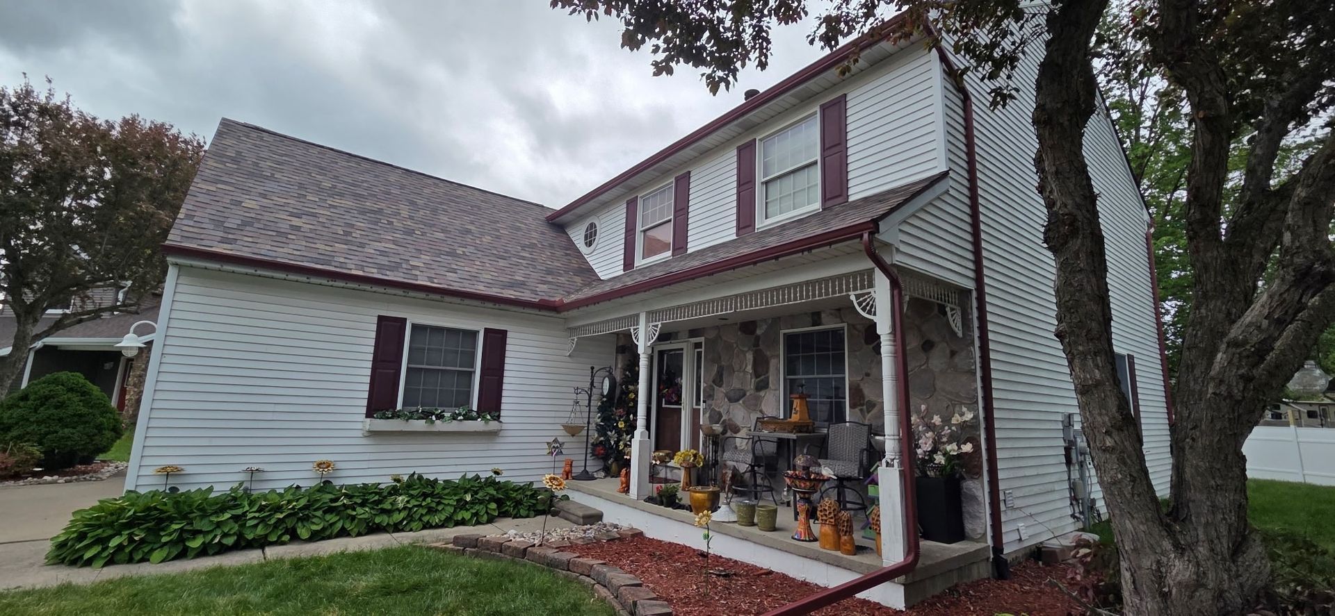 A white house with a porch and a tree in front of it