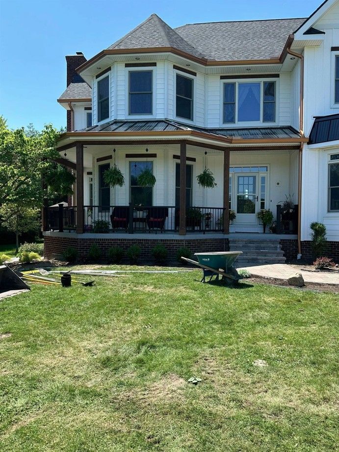 A large white house with a large porch and a wheelbarrow in front of it