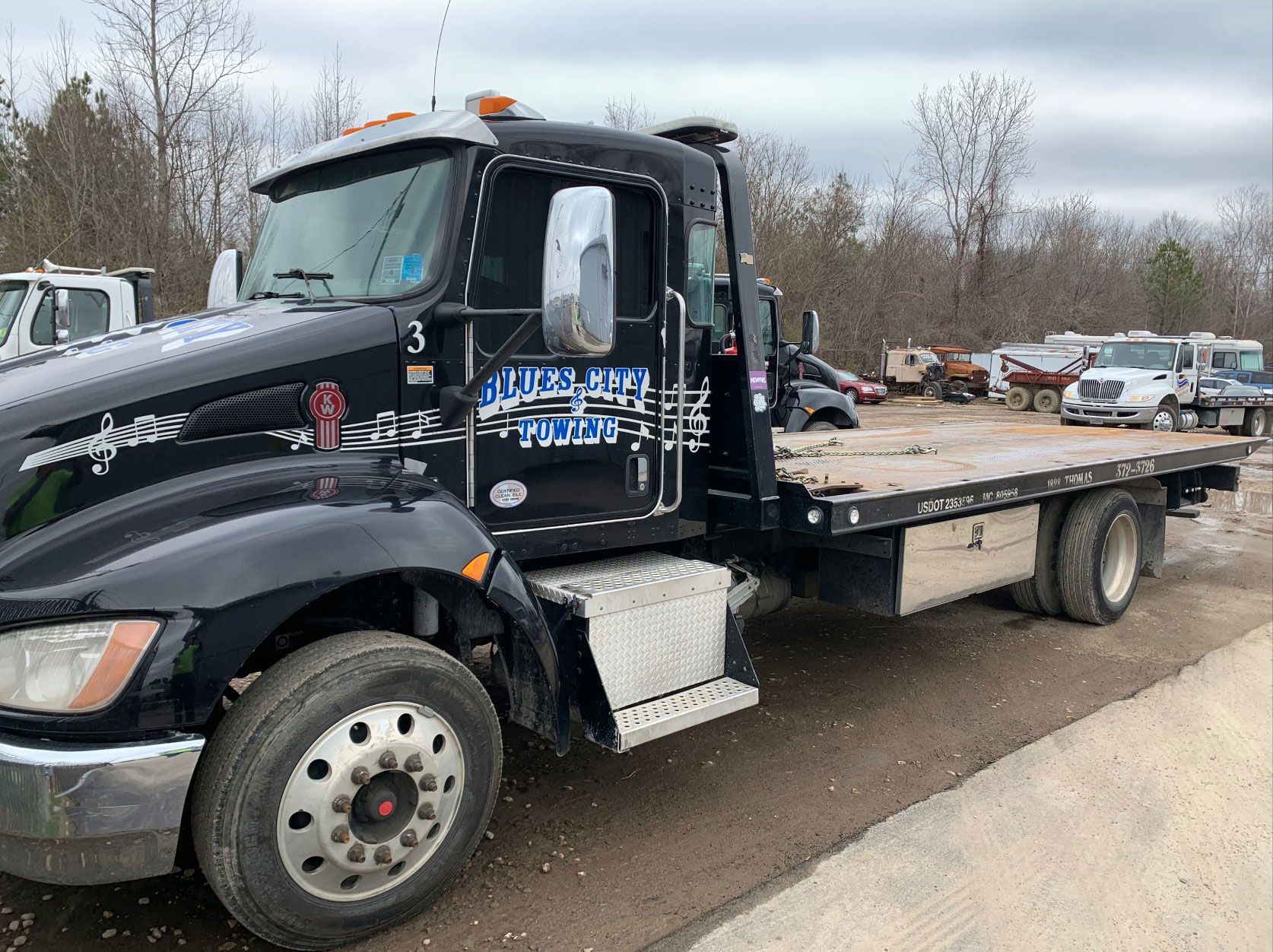 Black flatbed tow truck parked outdoors.