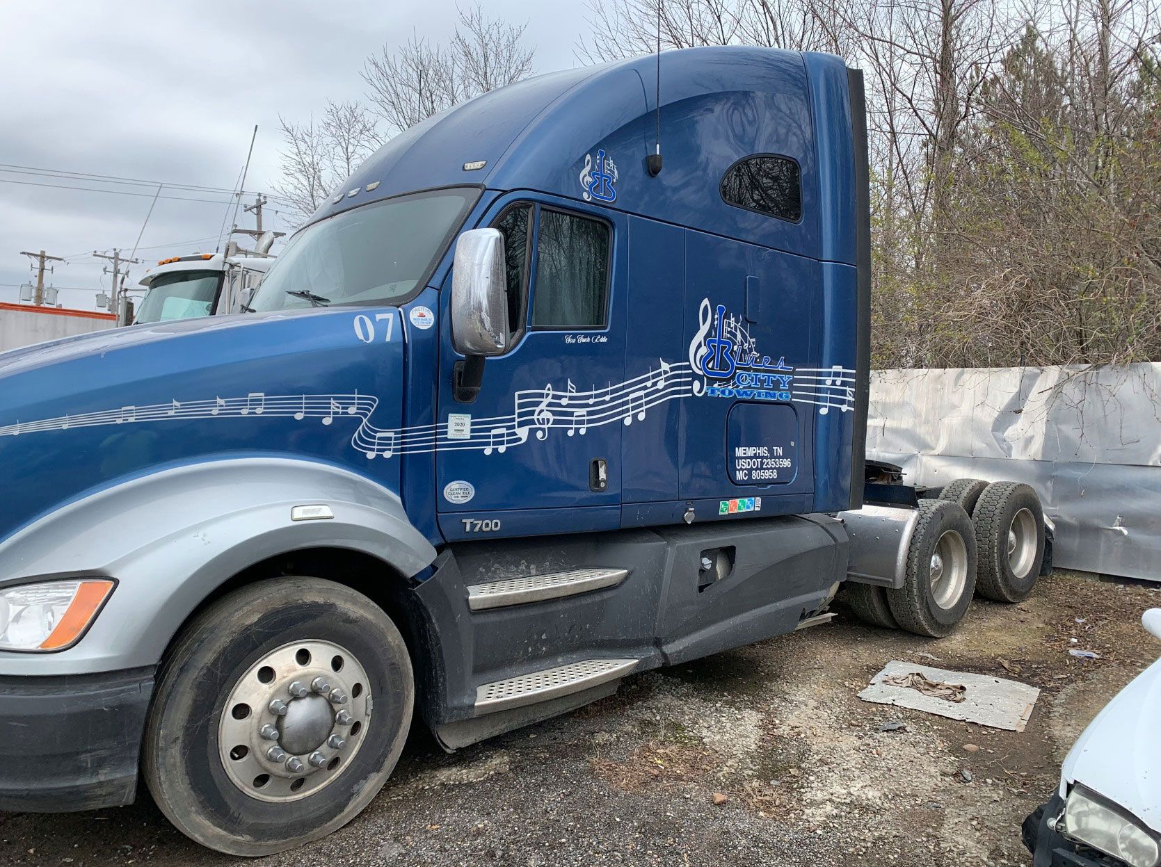 Blue semi-truck parked outdoors, featuring musical note design on the side.
