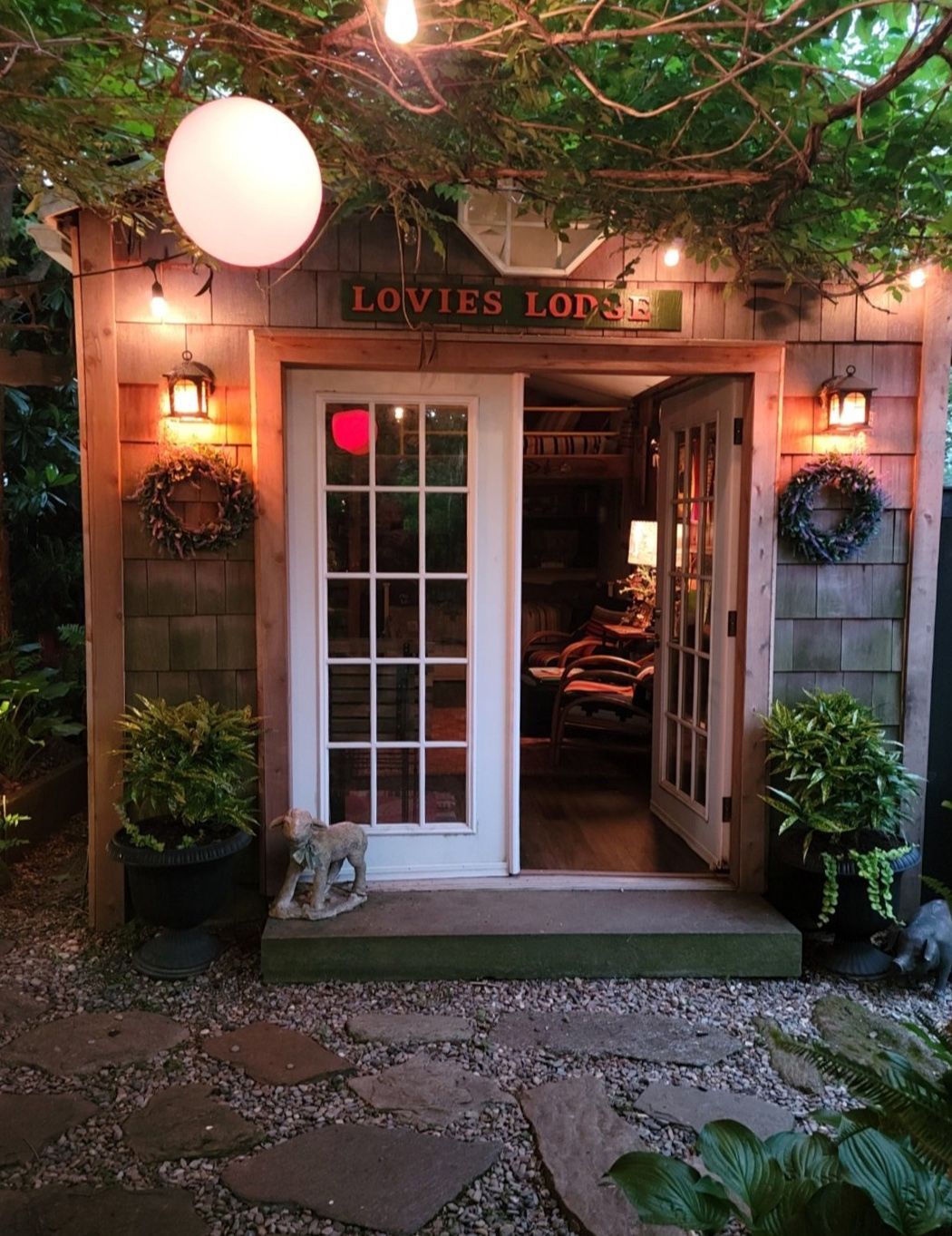 Cozy garden shop entrance with glass door, warm lights, and potted plants at dusk