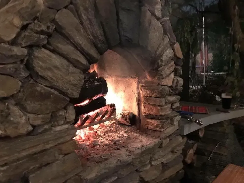 Stone fireplace with a small fire burning inside, lit by warm orange flames.