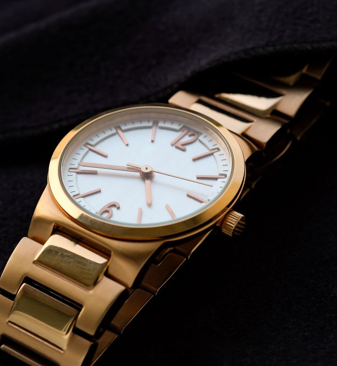 A gold watch with a white face and roman numerals