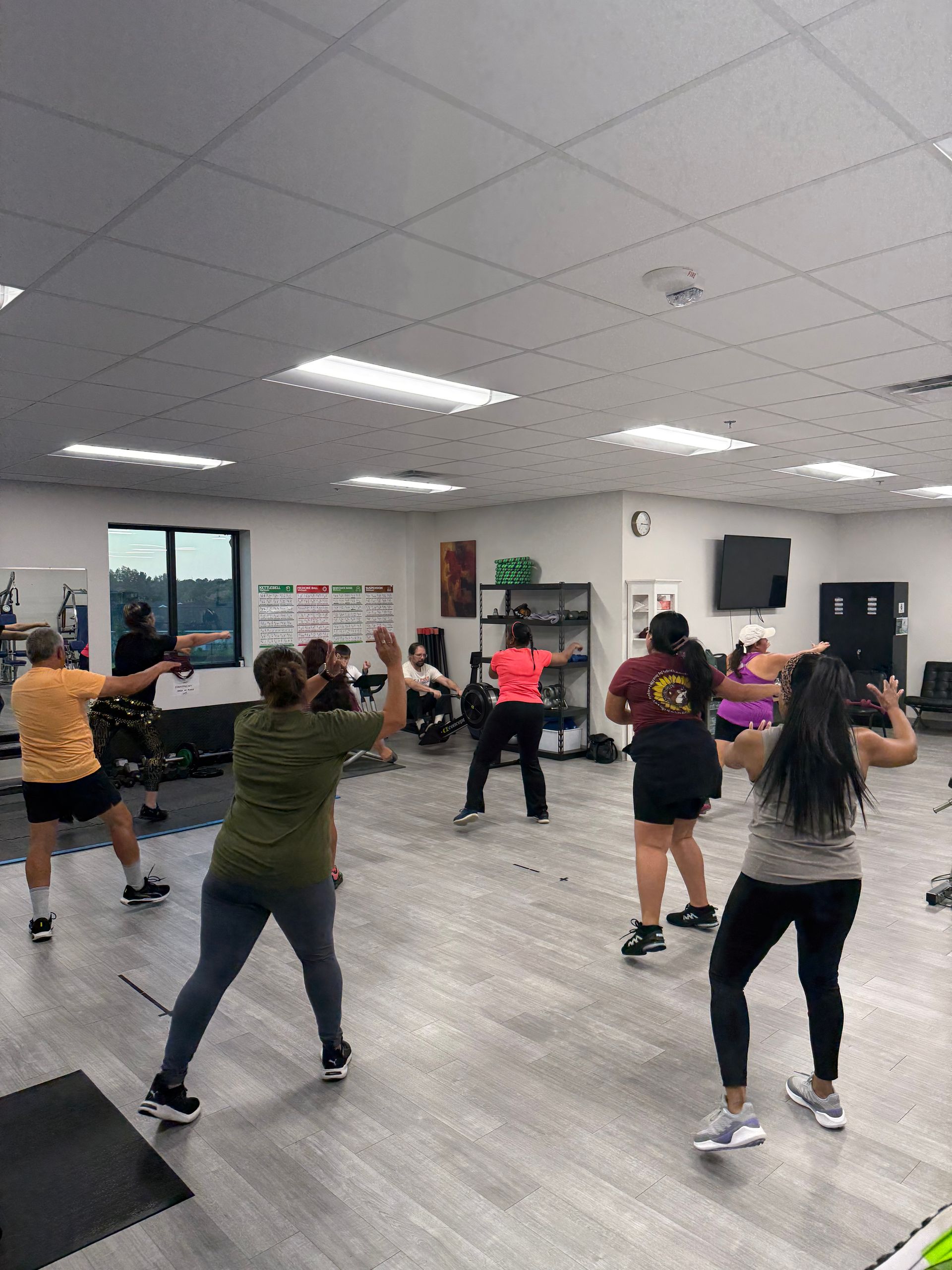People exercising in a bright indoor studio, following a group dance workout.