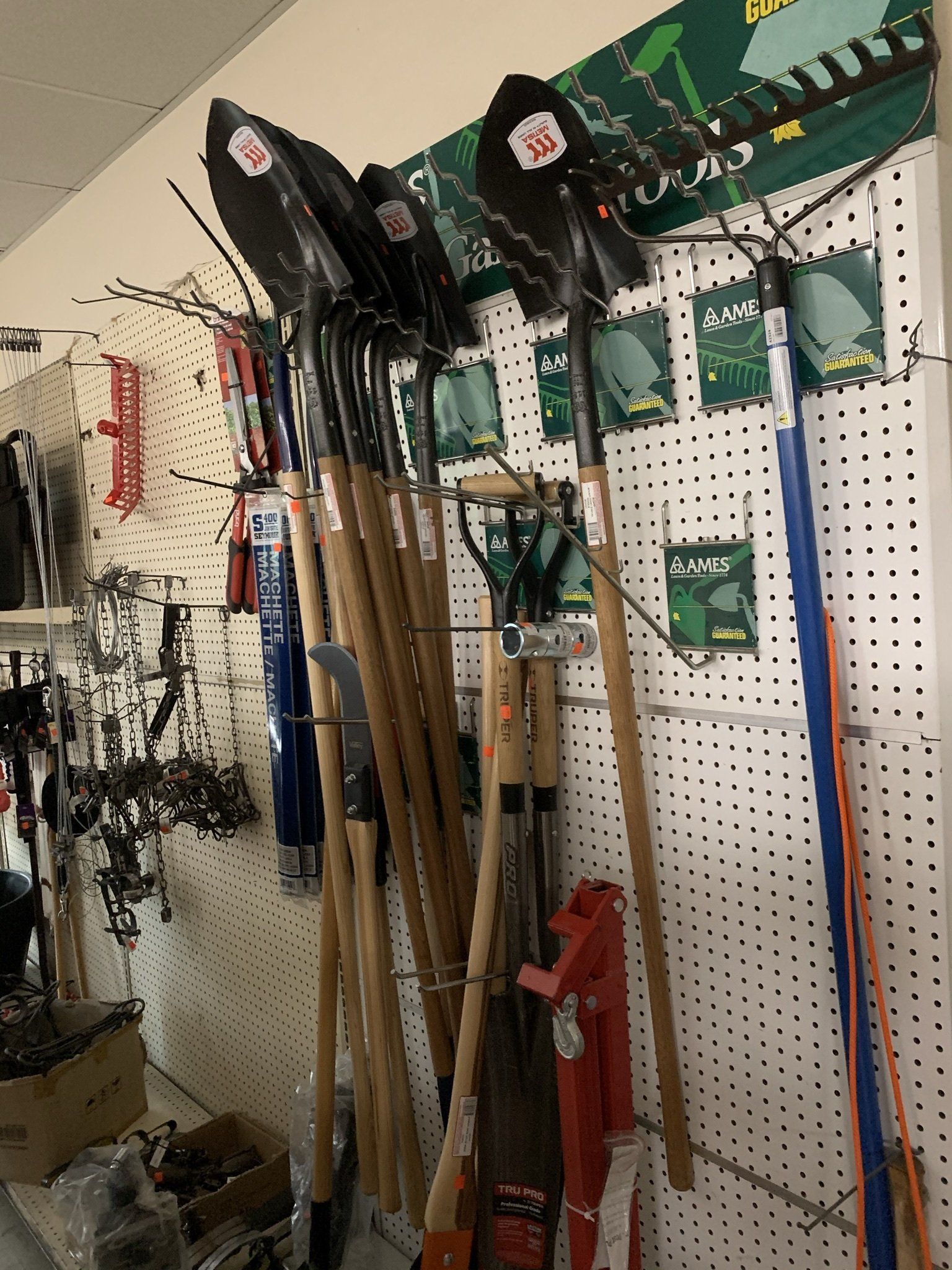 A bunch of shovels are hanging on a wall in a store.