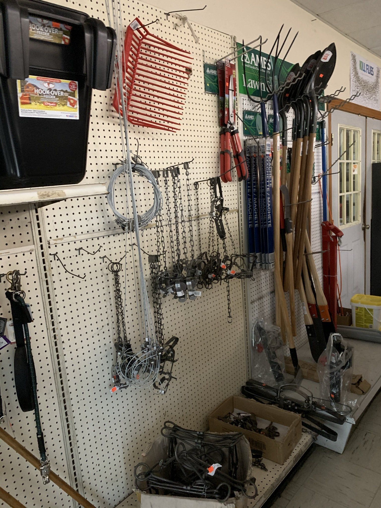 A bunch of shovels are hanging on a wall in a store.