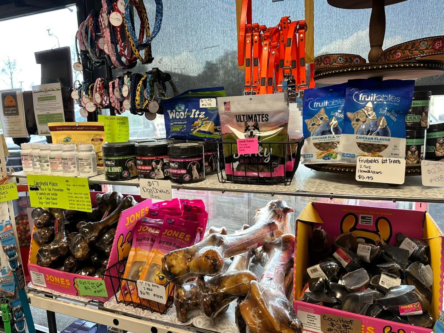A variety of dog treats and collars are displayed on a shelf in a store.