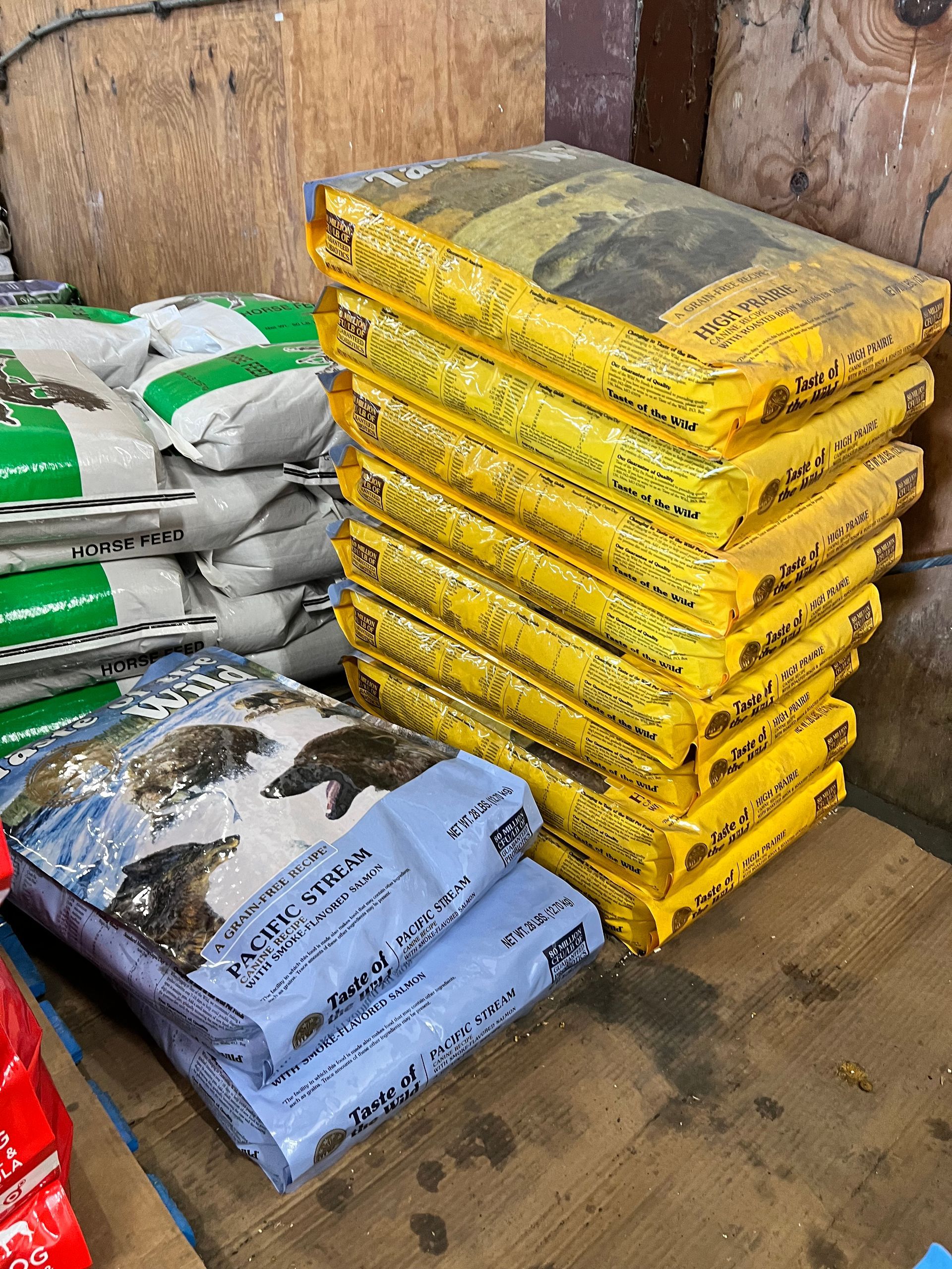 A pile of bags of dog food is stacked on top of each other on a wooden table.