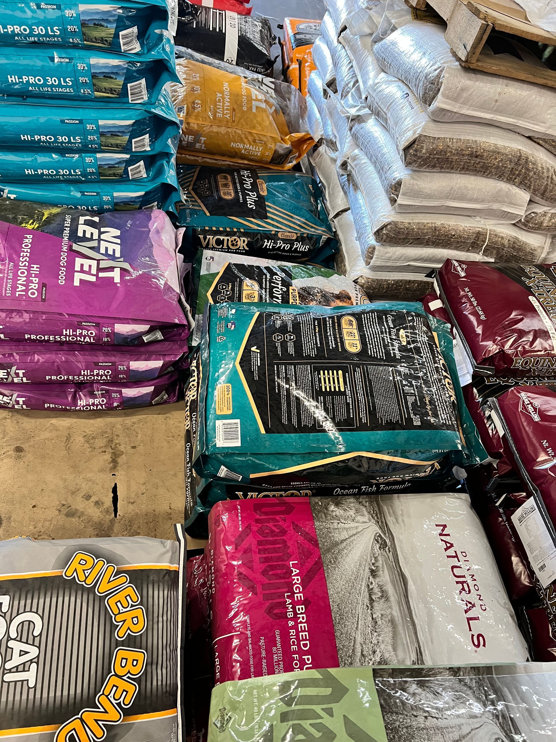 Different bags of dog food are stacked on top of each other in a store.