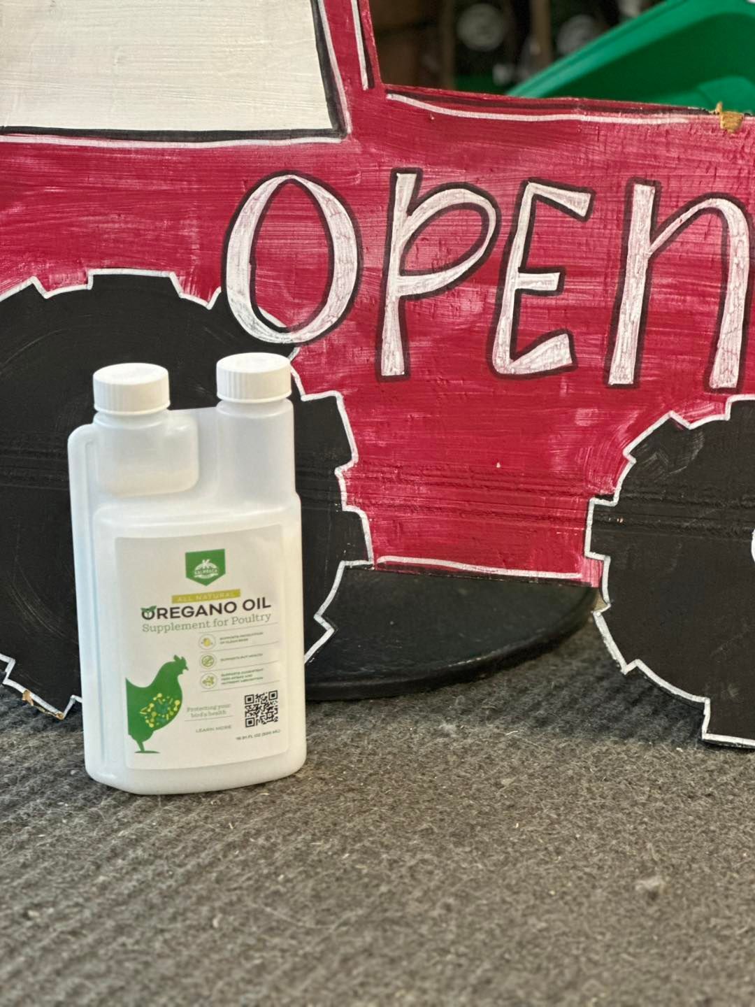 A bottle of oregano oil is sitting in front of a sign that says open.