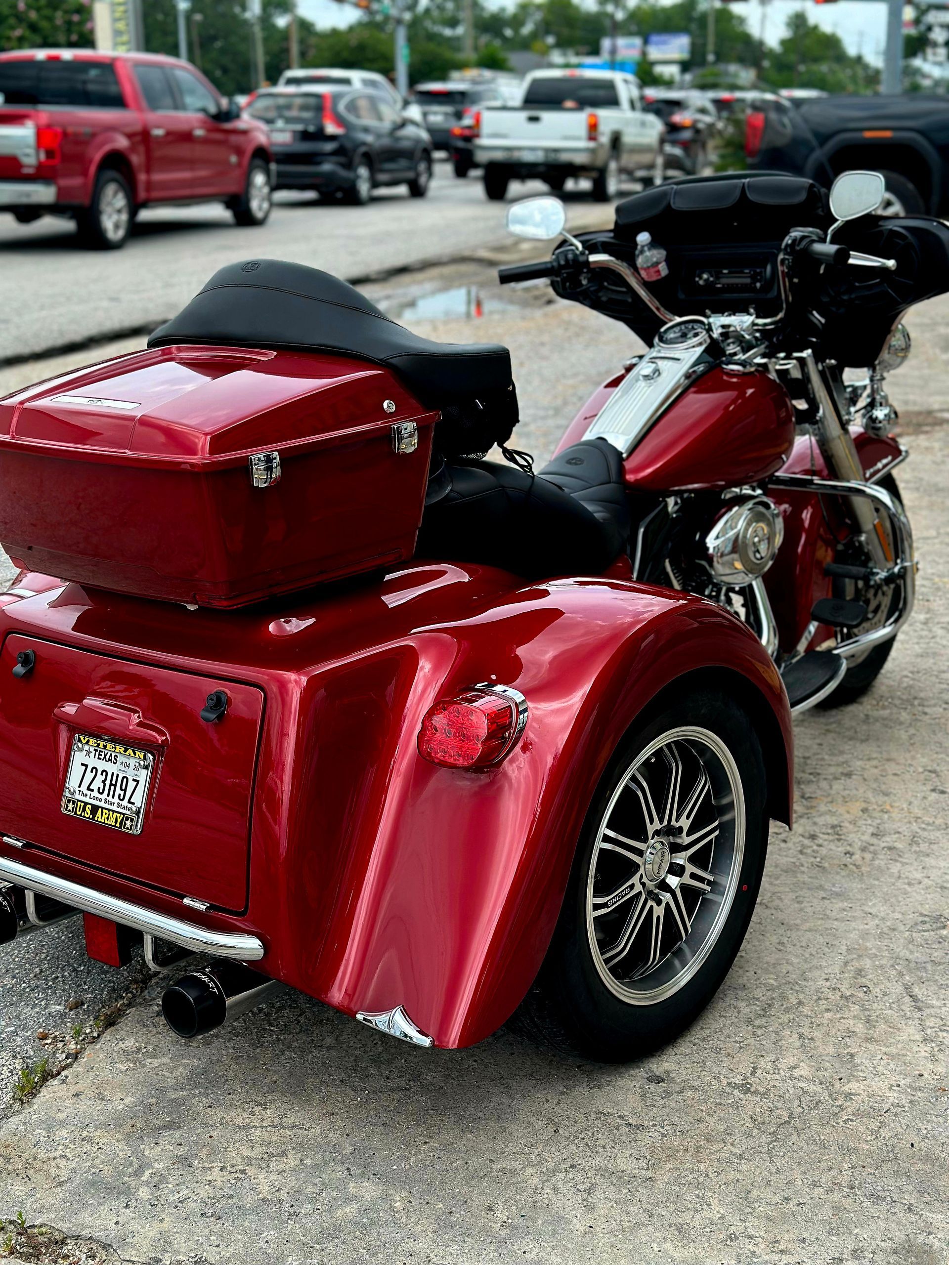 A red motorcycle with three wheels is parked on the side of the road.