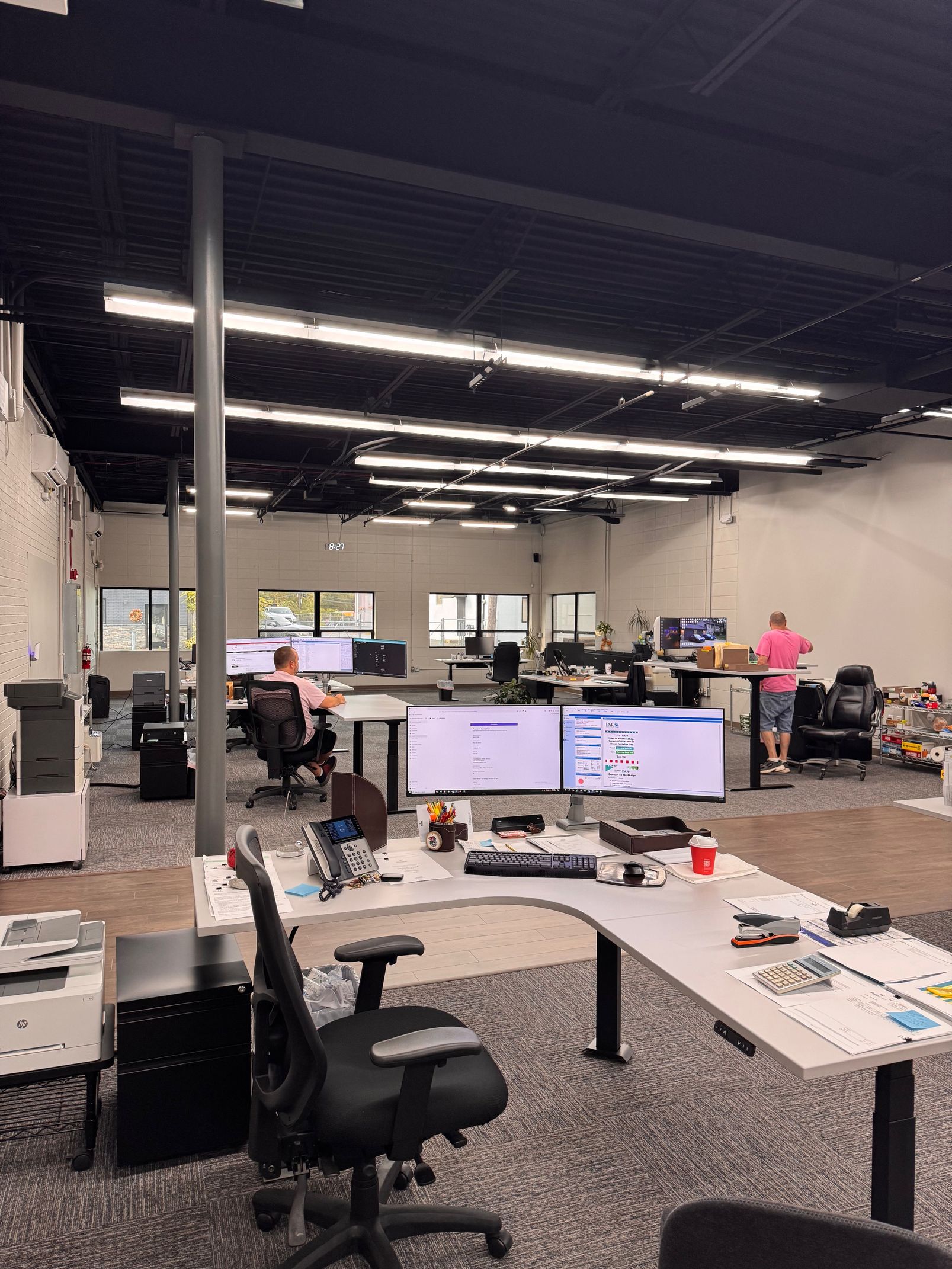 Open office with desks, computers, and employees.