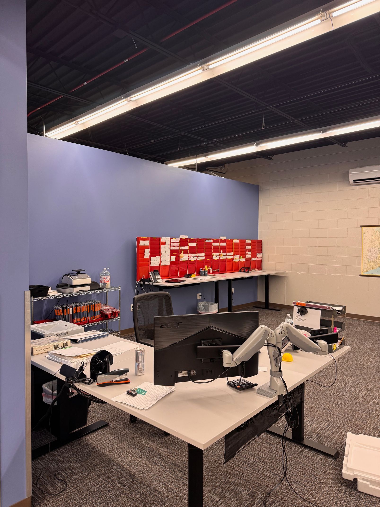 Office workspace with desks, computers, and colorful wall decorations.