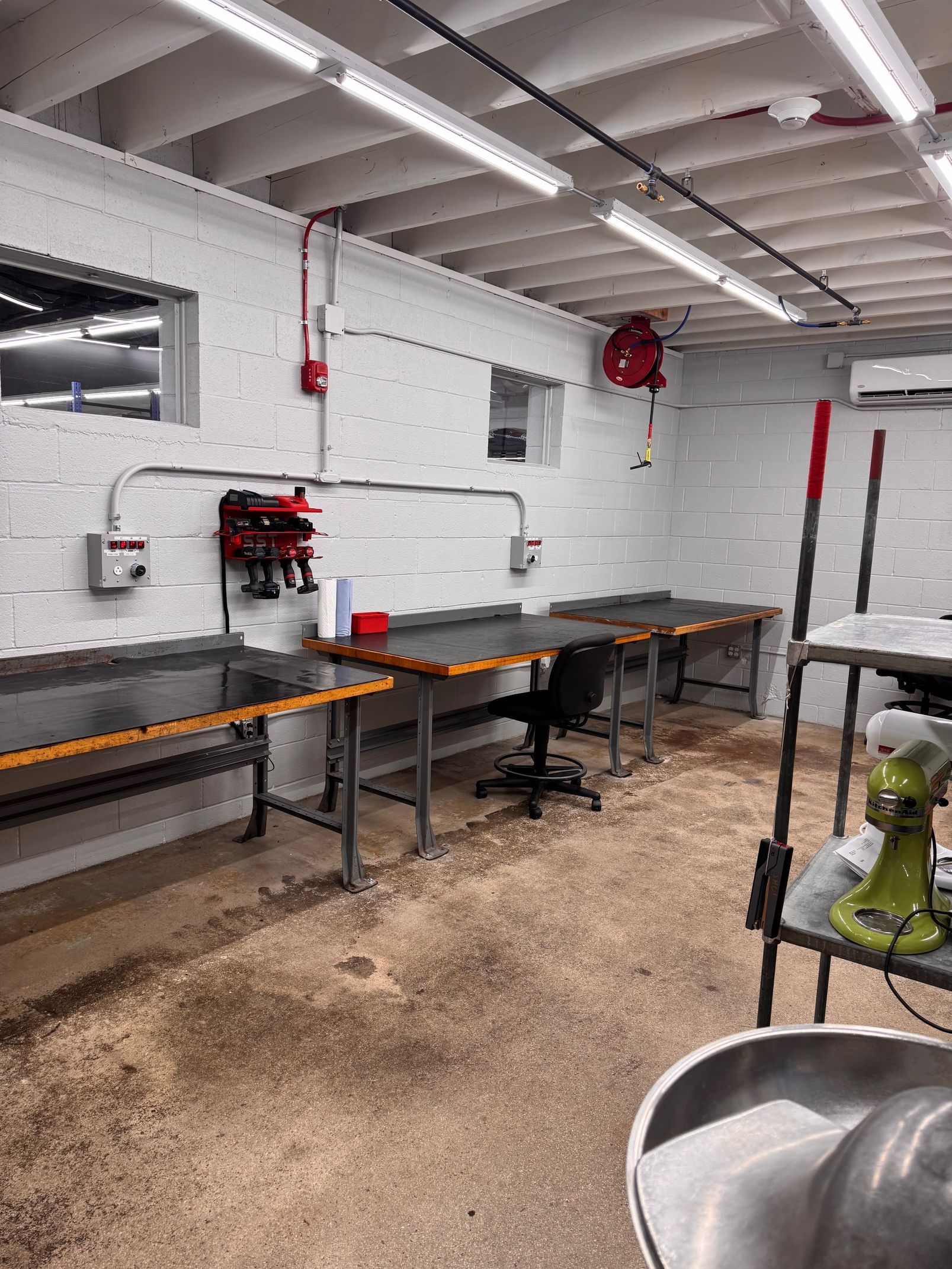Workshop interior with workbenches, tools, and a chair.
