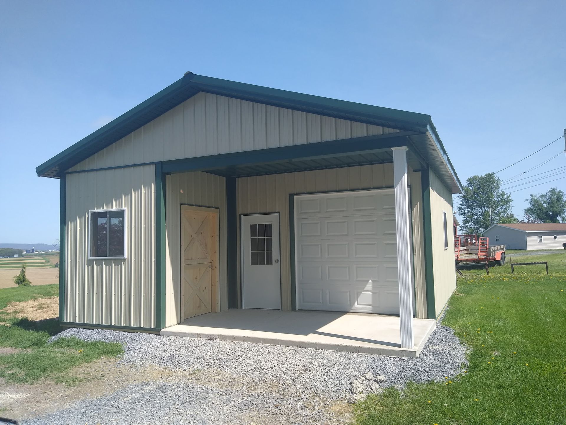 Small beige garage with a white roll-up door and open side entry on a gravel driveway.