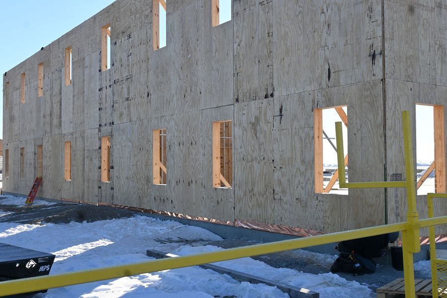 Exterior wall of a building under construction, with open window frames in a snowy setting.
