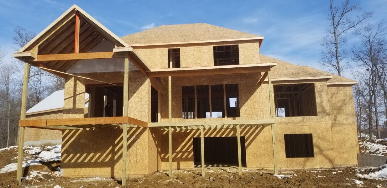 House under construction with exposed wood framing and a partially built deck.