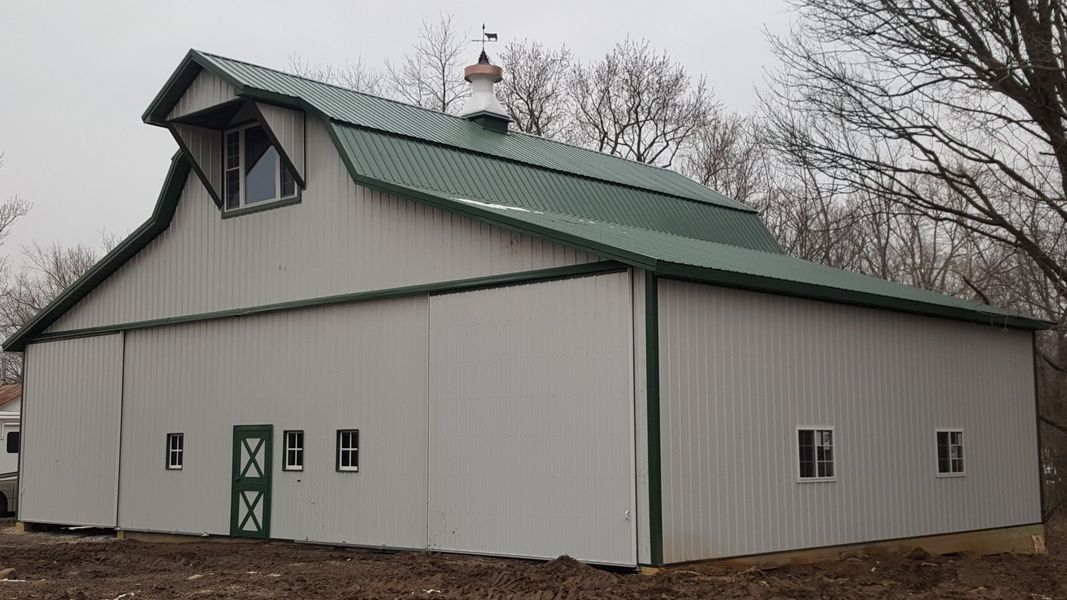 White barn with green roof and trim, several windows, and a dormer.