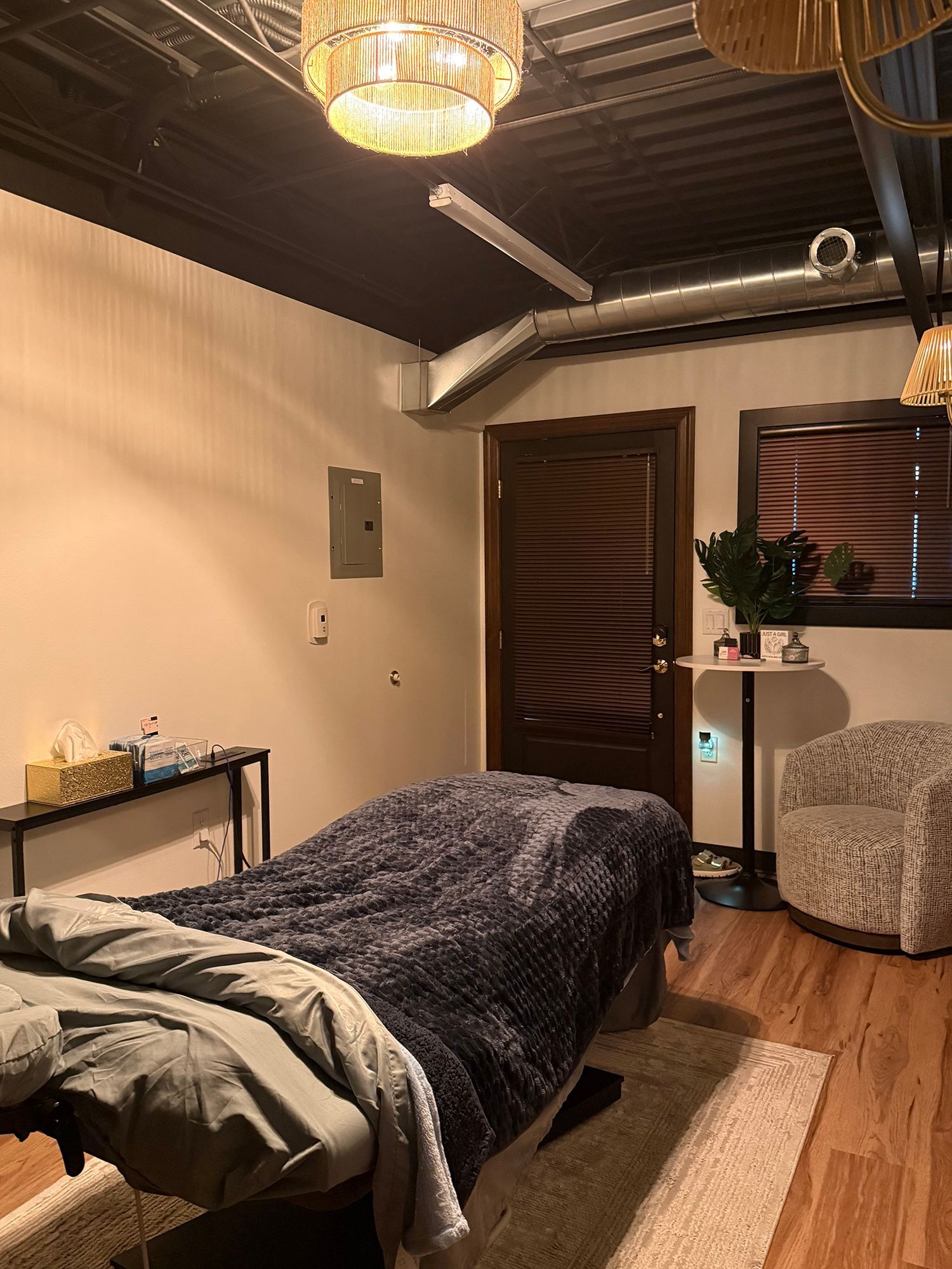 Cozy spa room with a bed, rug, small table, wood ceiling, and wall-mounted TV in warm lighting