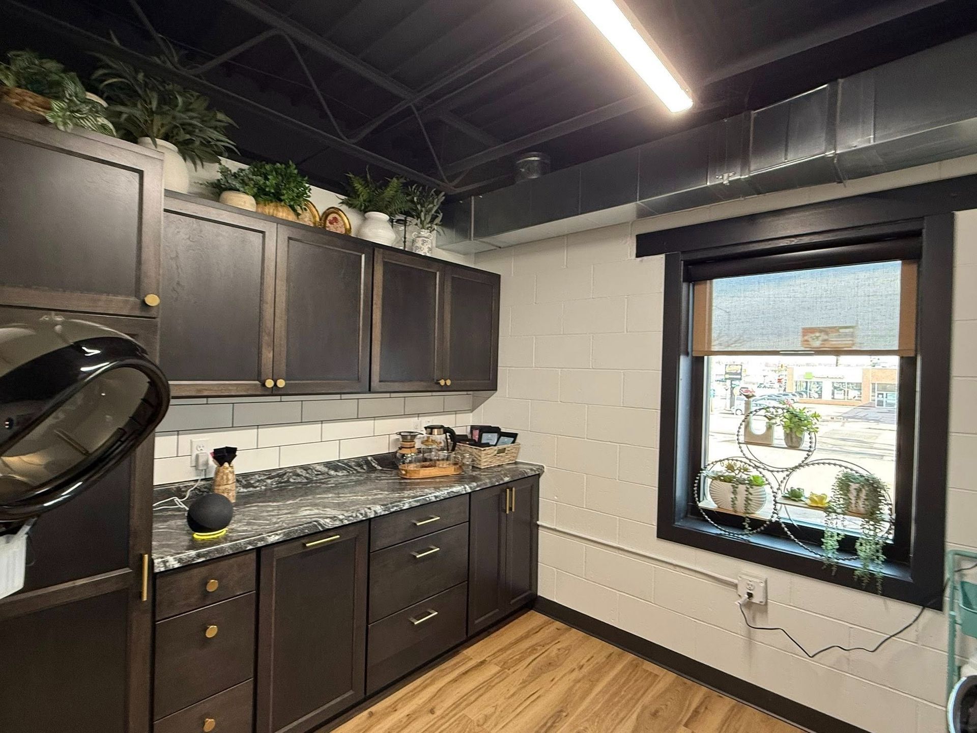 Modern kitchen with dark cabinets, granite countertop, and a window above a sink under a black ceiling.