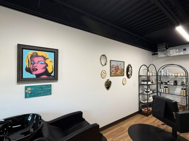 Modern salon interior with wall art, mirrors, styling chairs, and display shelves.