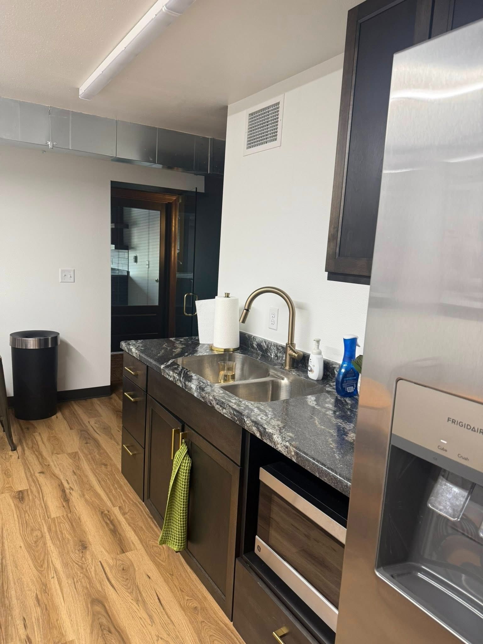 Modern kitchen with dark cabinets, granite countertop, sink, and wood floors