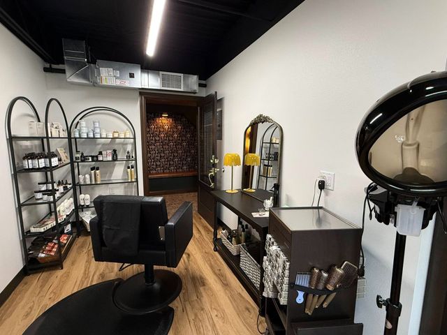 Modern salon interior with styling chair, mirrors, shelves, and a hair dryer station