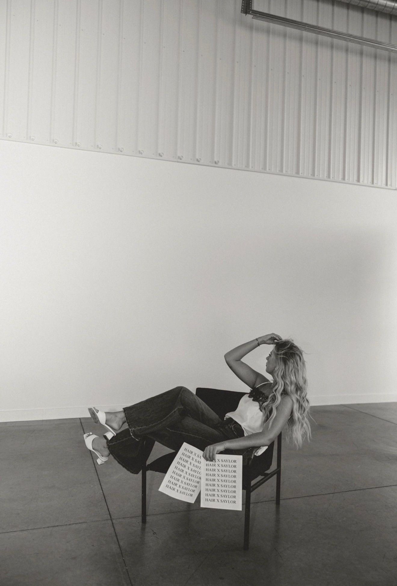 Person reclining in a chair in a large empty room, with a sketchbook or notes on their lap.