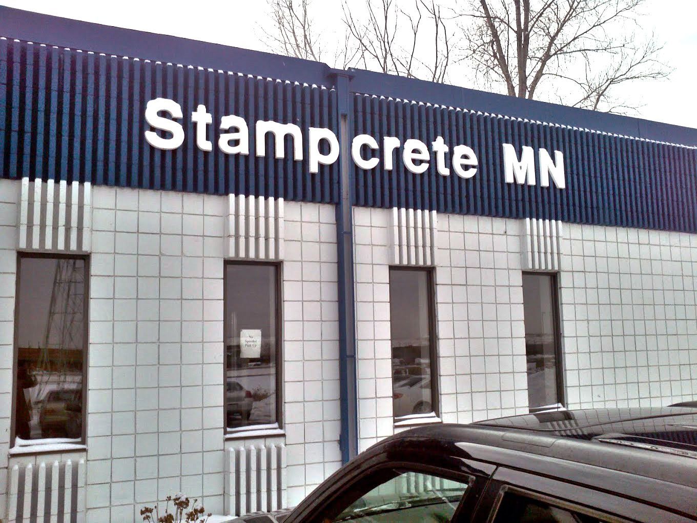 a car is parked in front of a building that says stampcrete mn