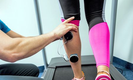 A man is stretching a woman 's foot with a rubber band.